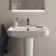 Waschtisch von Ideal Standard mit breiter, rechteckiger Schüssel, moderner Armatur und Ablagefläche, montiert an einer Wand mit grauer Farbe, Handtuchhalter an der Seite.